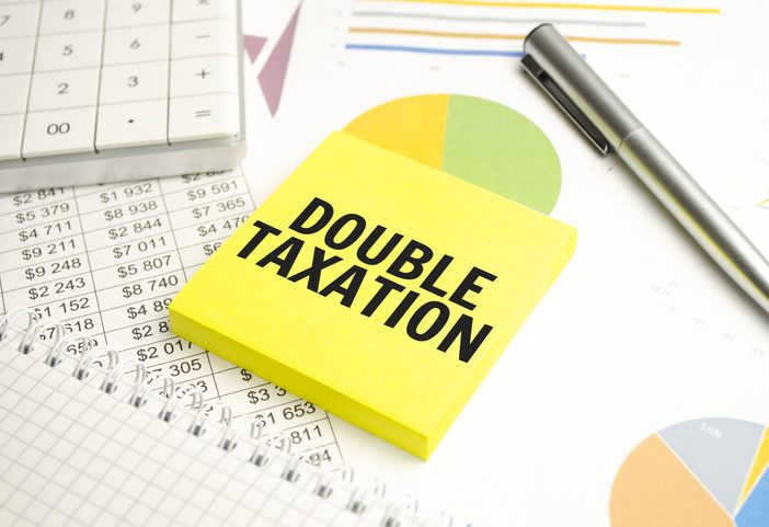 open notebook in a closed notebook. near the calculator.text on white paper. DOUBLE TAXATION