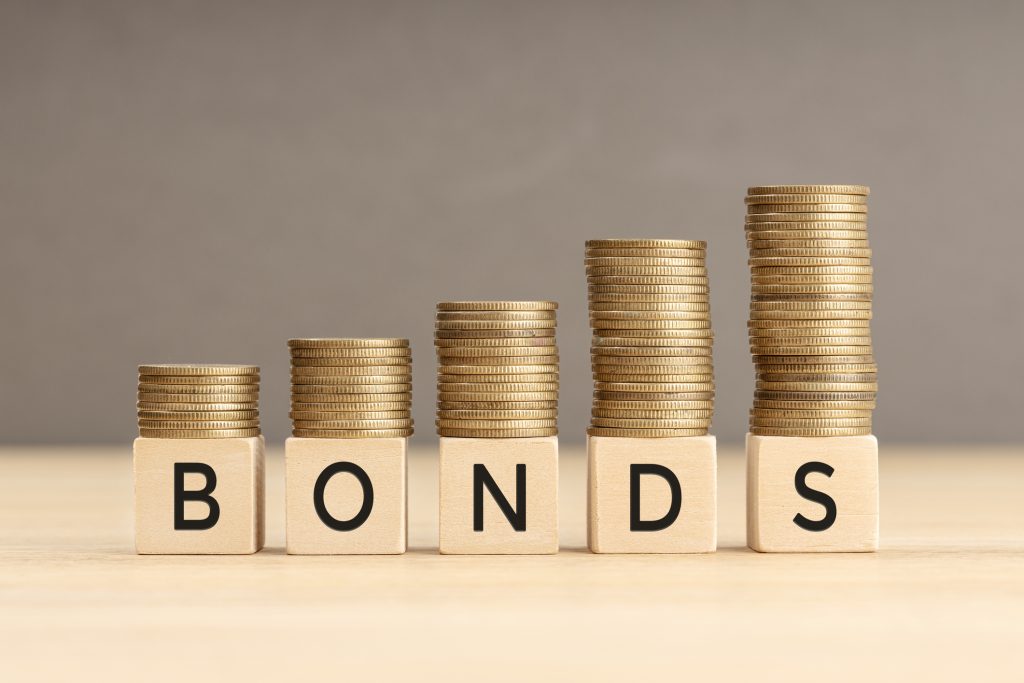 Bonds word in wooden blocks with coins stacked in increasing stacks. Bonds increasing concept. Copy space