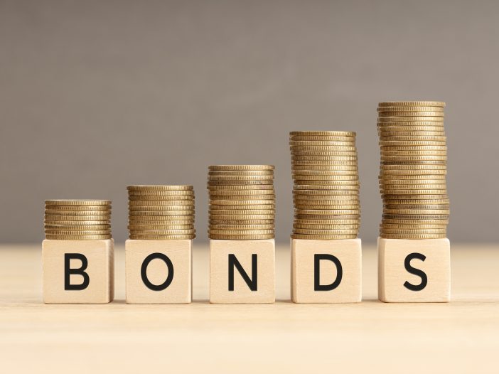 Bonds word in wooden blocks with coins stacked in increasing stacks. Bonds increasing concept. Copy space